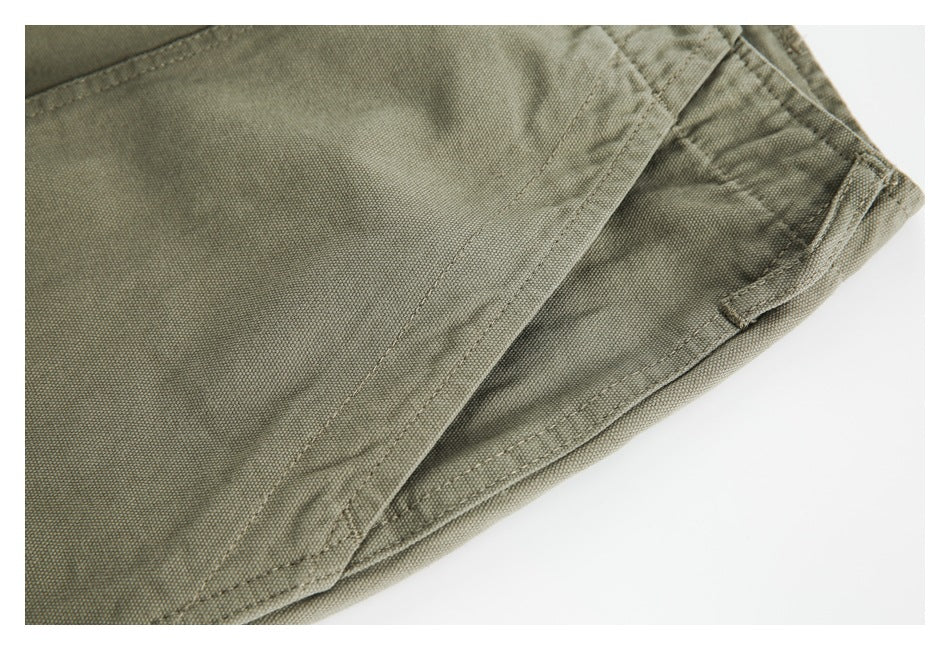 Close-up of olive-khaki garment fabric with overlapping stitched seams and a folded edge.