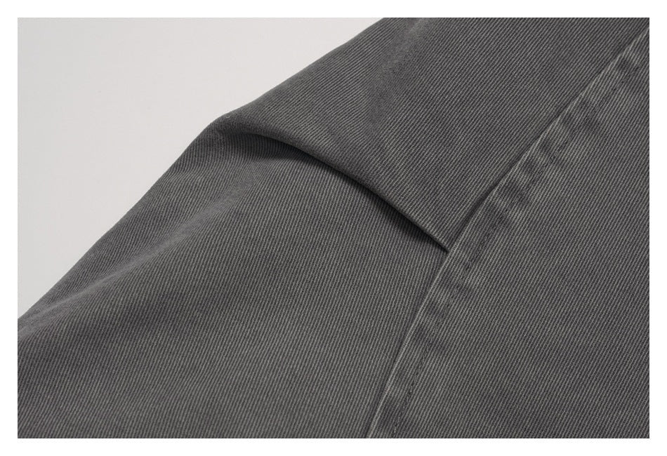 Close-up of dark gray jacket fabric with a folded seam and fine diagonal texture.