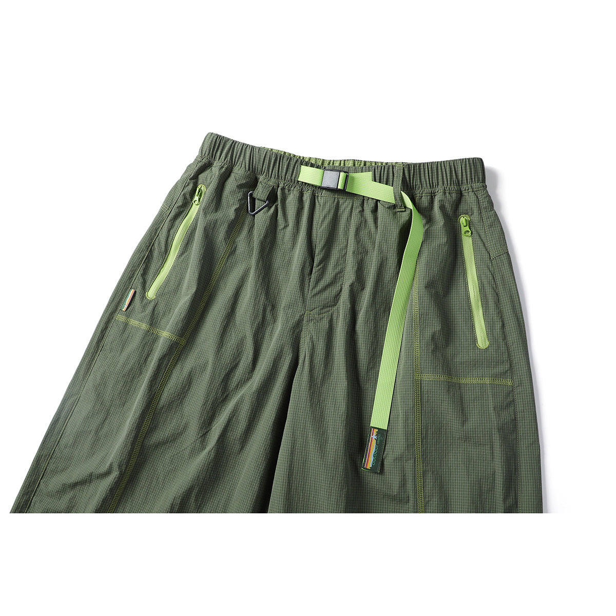 Front view of loose olive grid-pattern trousers with an elastic waist, lime belt and two lime zip pockets.