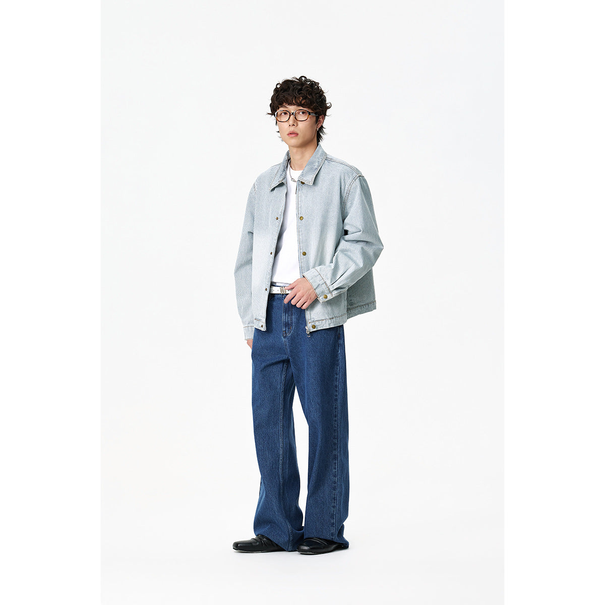 Full-length view of a model in a light blue-and-white striped jacket, white shirt and wide-leg dark blue jeans.