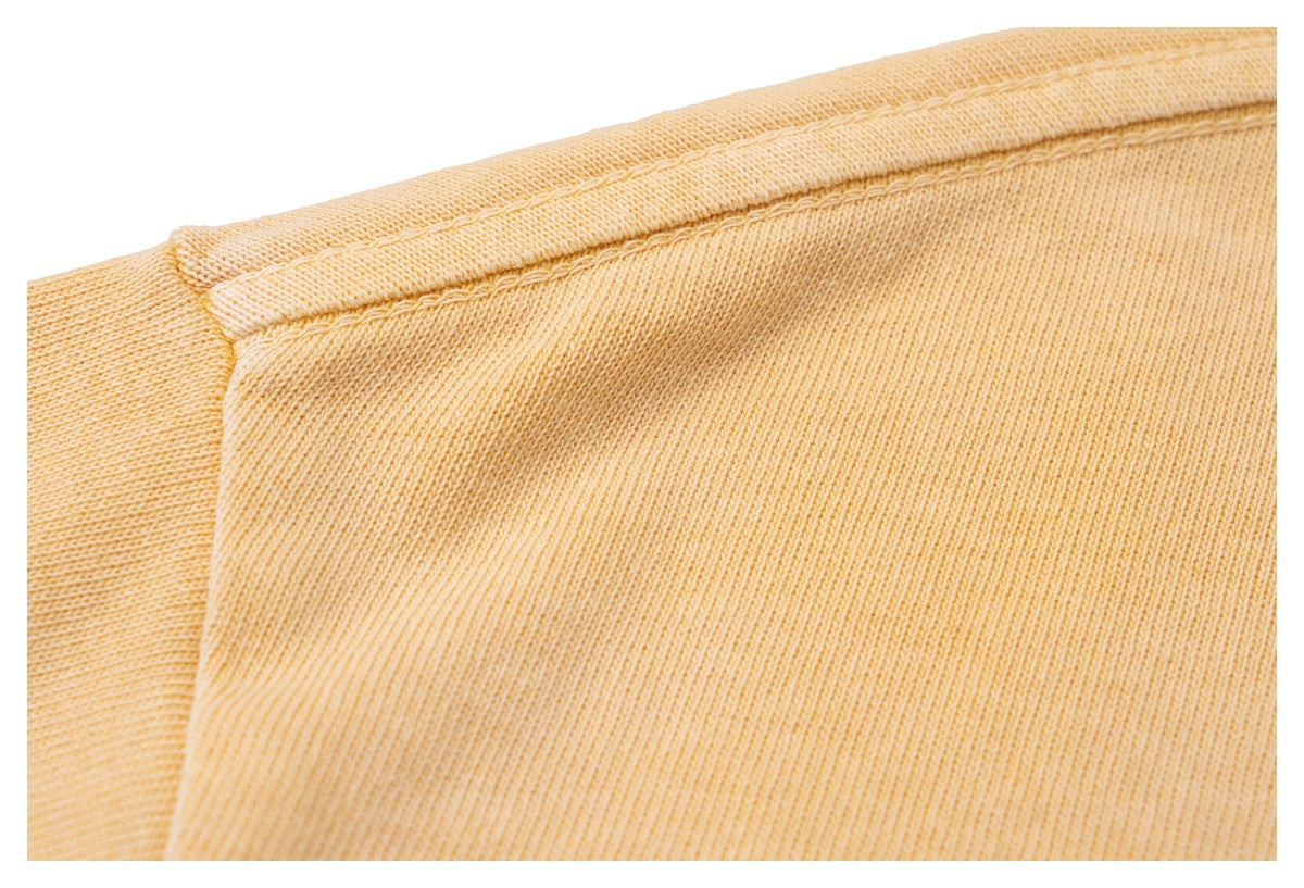Close-up of the golden-yellow sweatshirt’s shoulder seam and fabric.