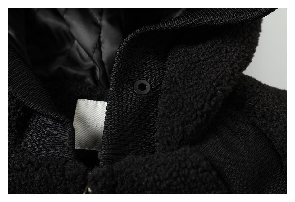 Close-up of a black textured jacket showing a snap fastener, ribbed trim and a partially visible inner label.