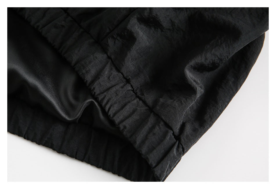 Close-up of a black garment's gathered hem and dark inner lining.