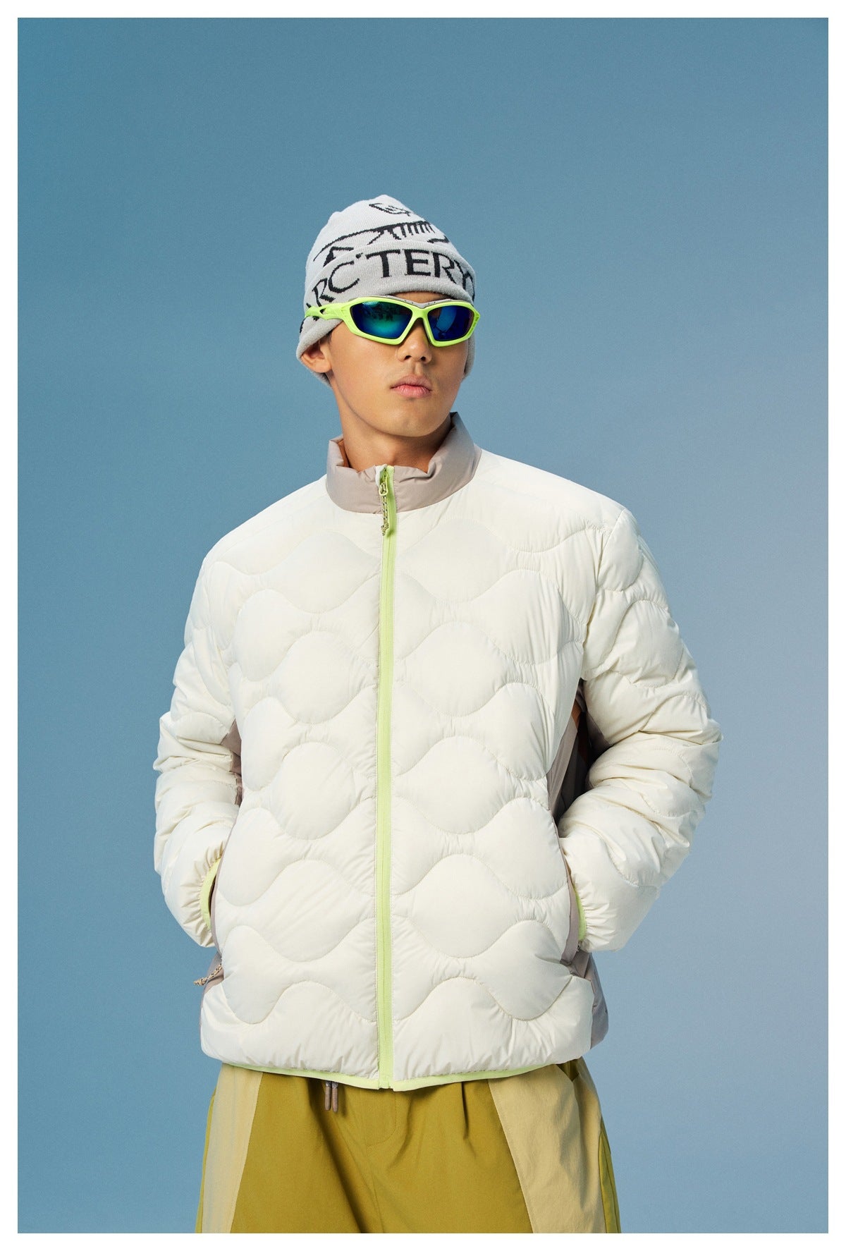 Front view of a model wearing a white wave-quilted jacket with a taupe collar and bright lime zipper.