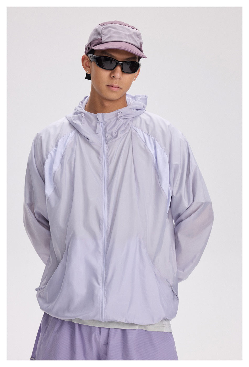 Front view of a model wearing a pale lavender hooded zip jacket with curved contrast mesh panels.