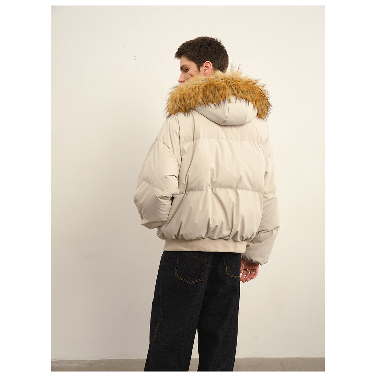 Model showing the back of a light beige puffer jacket with a tan fur-trimmed hood.