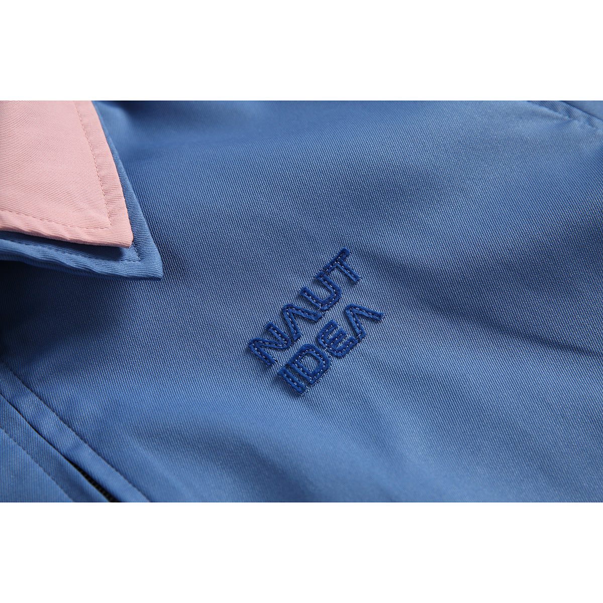 Close-up of dark blue embroidered lettering on a blue jacket beside part of its pink collar.