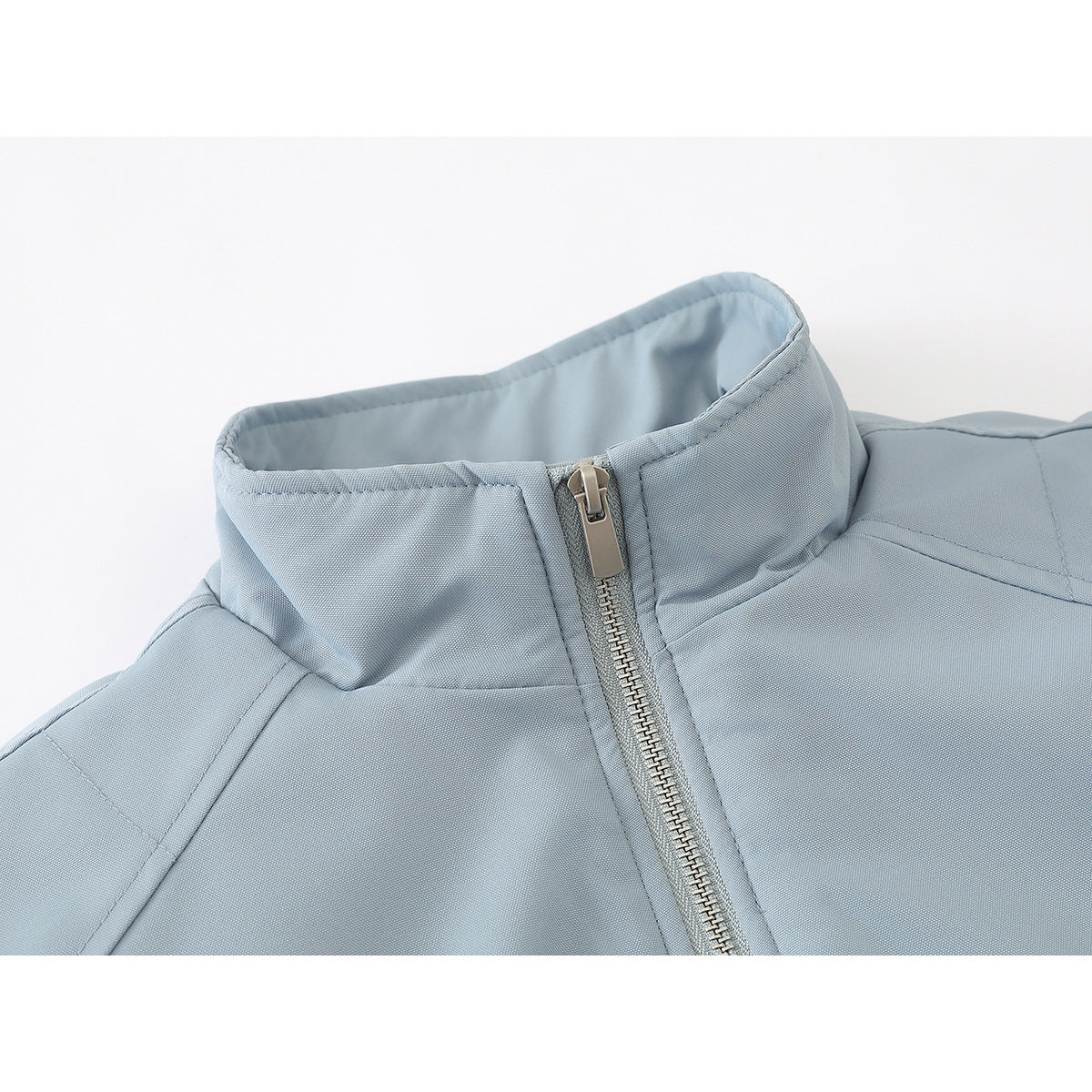 Close-up of a pale blue jacket’s raised collar and silver front zipper.