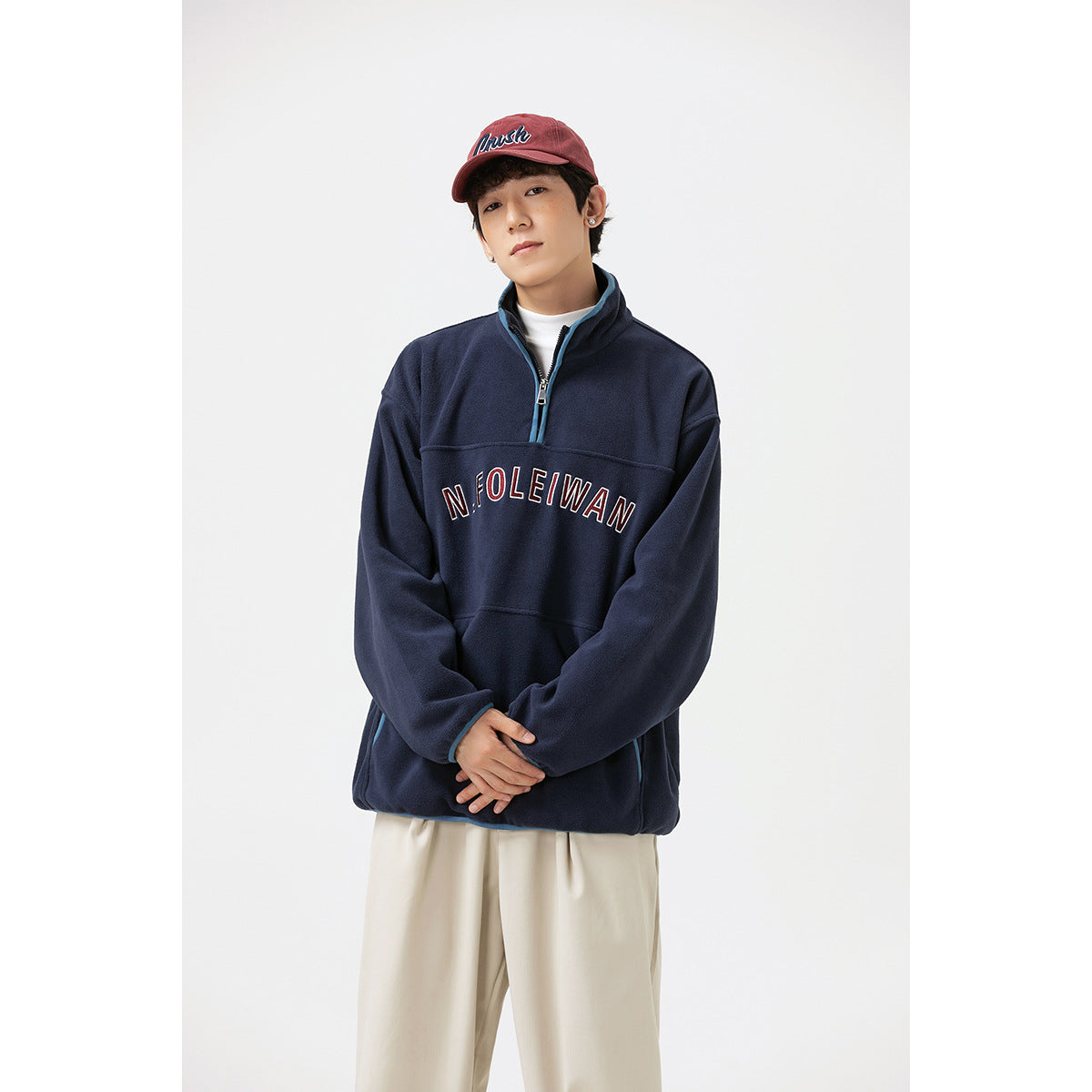 Closer view of a model wearing a navy quarter-zip pullover with blue trim and outlined chest lettering.