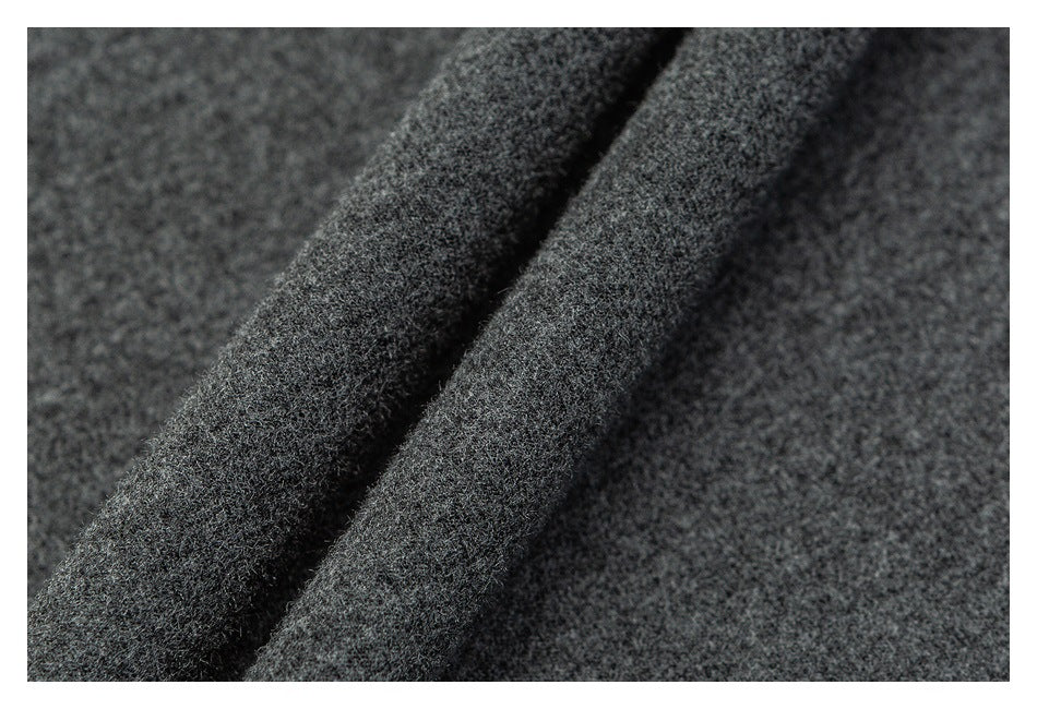 Close-up of dark charcoal gray fabric with a soft-looking textured surface and a folded edge.