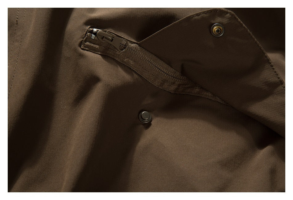 Close-up of a dark brown jacket's front zipper beneath a snap-fastened storm flap.
