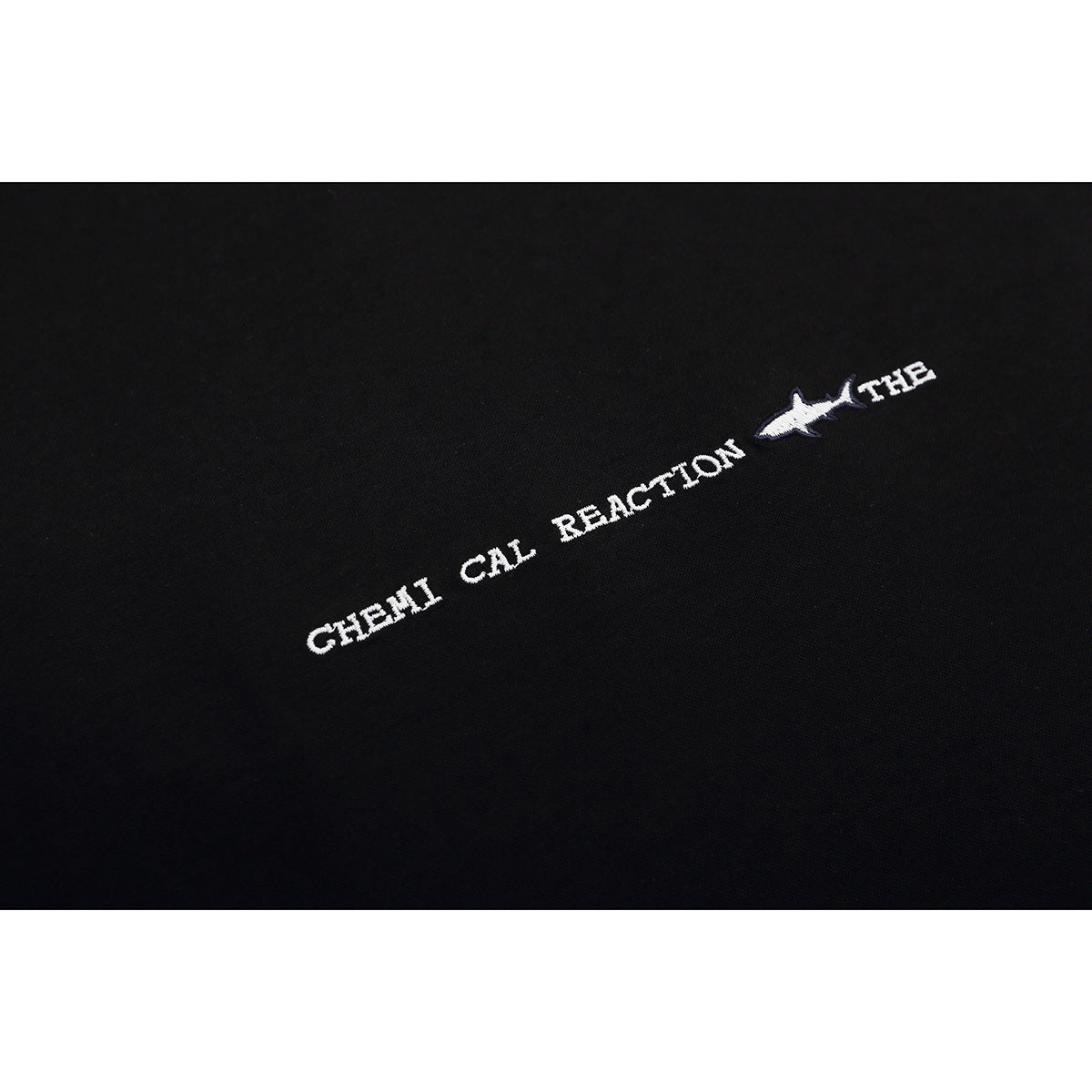 Close-up of white embroidered lettering and a small shark motif on black fabric.