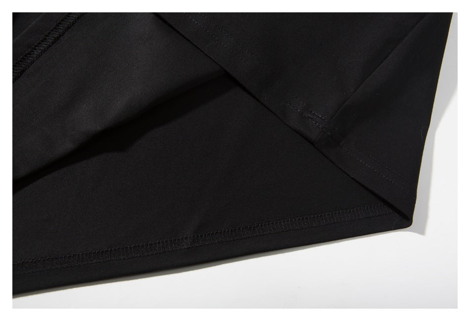 Close-up of the black T-shirt's fabric and stitched sleeve and lower hem seams.