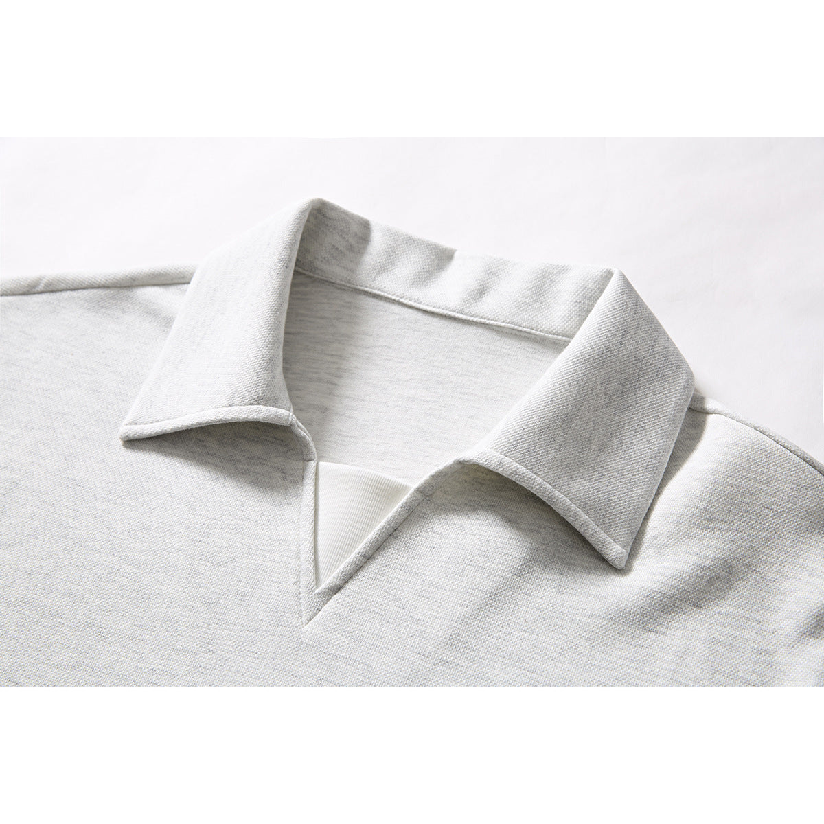 Close-up of a light gray polo shirt's wide pointed collar and open V-neck.