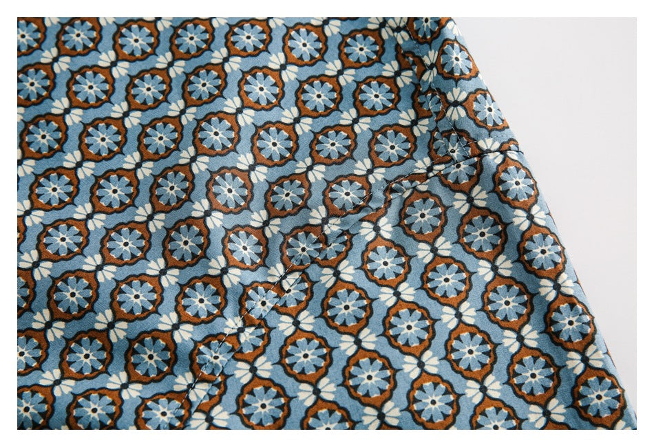 Close-up of blue floral shirt fabric showing a curved stitched seam and finished edge.