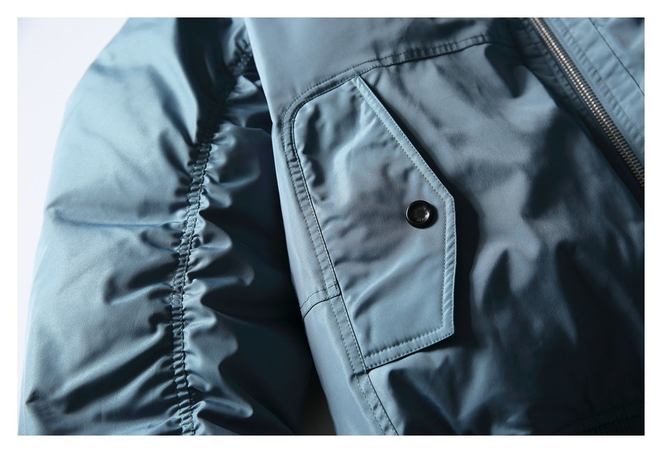 Close-up of a buttoned flap pocket, sleeve seam, and zipper on the blue jacket.