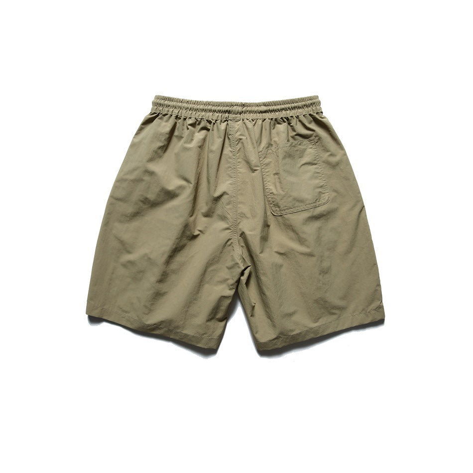 Back view of olive-khaki shorts with an elastic waistband and one rear patch pocket, laid flat on white.