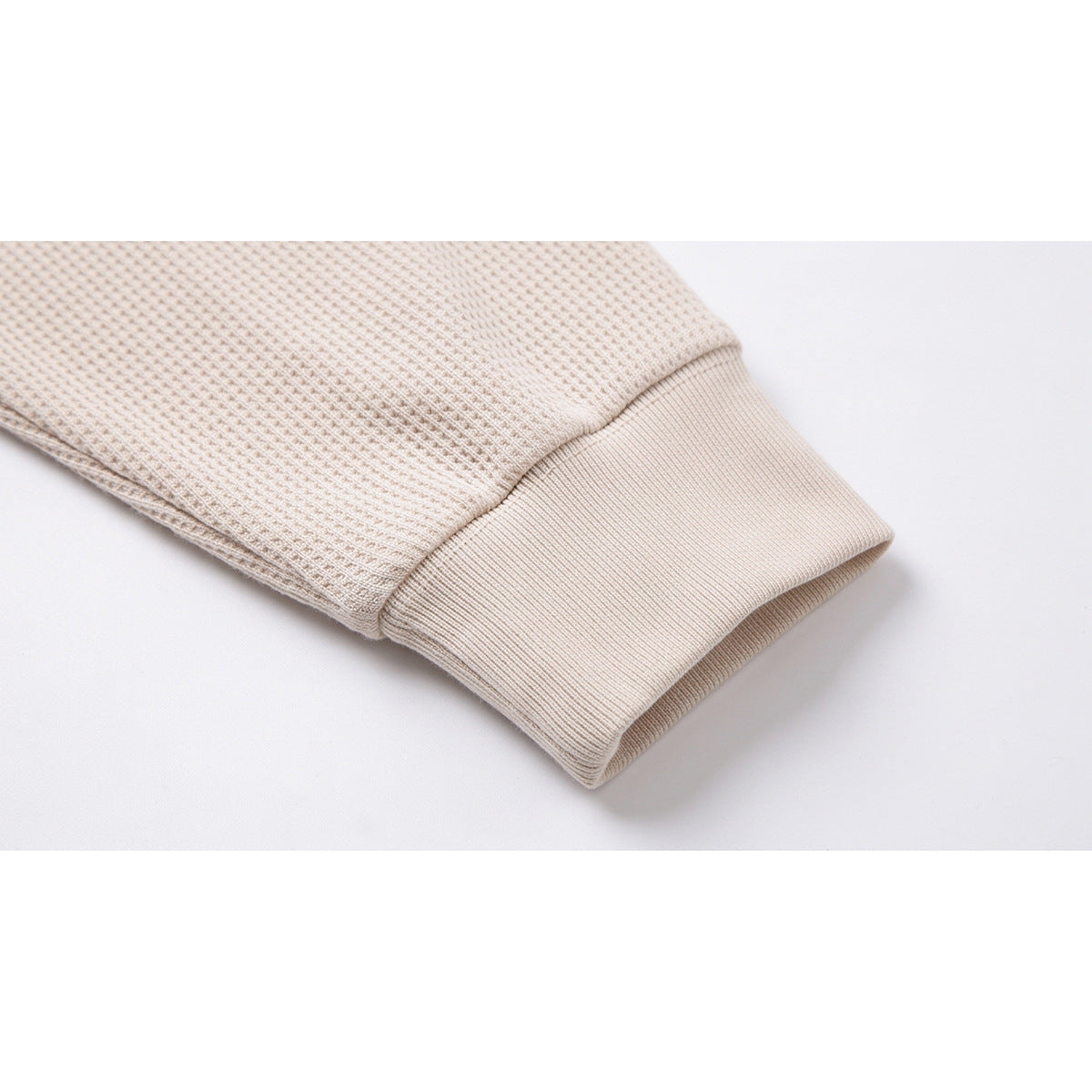 Close-up of the cream polo shirt's long sleeve and wide ribbed cuff.
