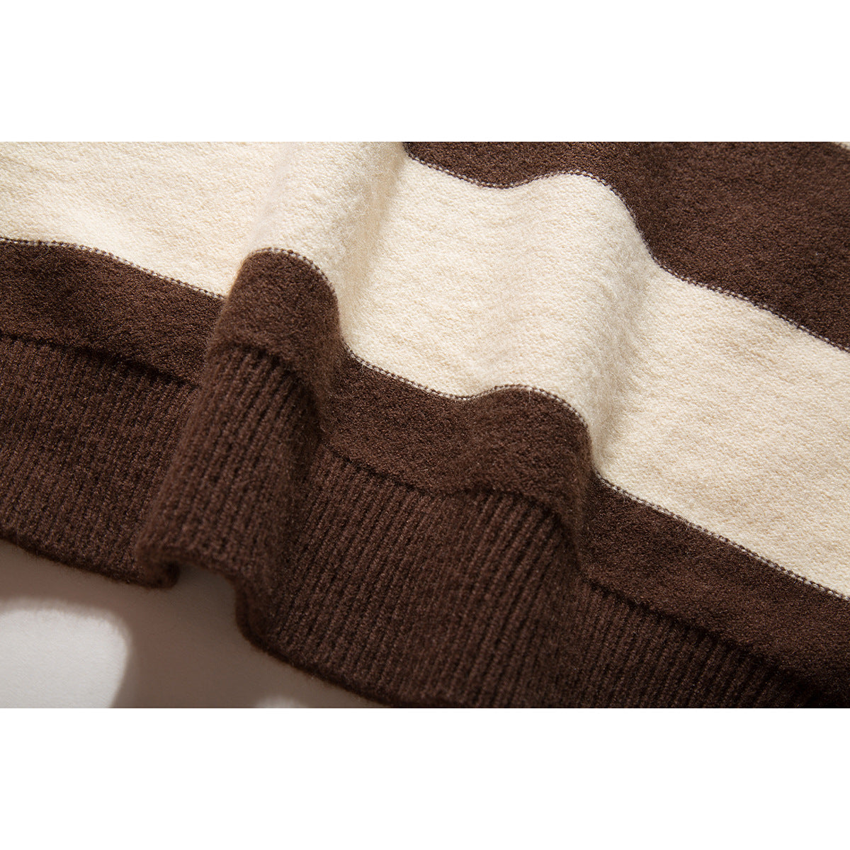 Close-up of the brown ribbed cuff and cream-and-brown striped knit of a sweater.
