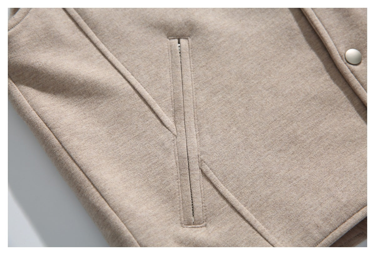 Close-up of a beige jacket's narrow vertical zip pocket and a silver-tone snap.