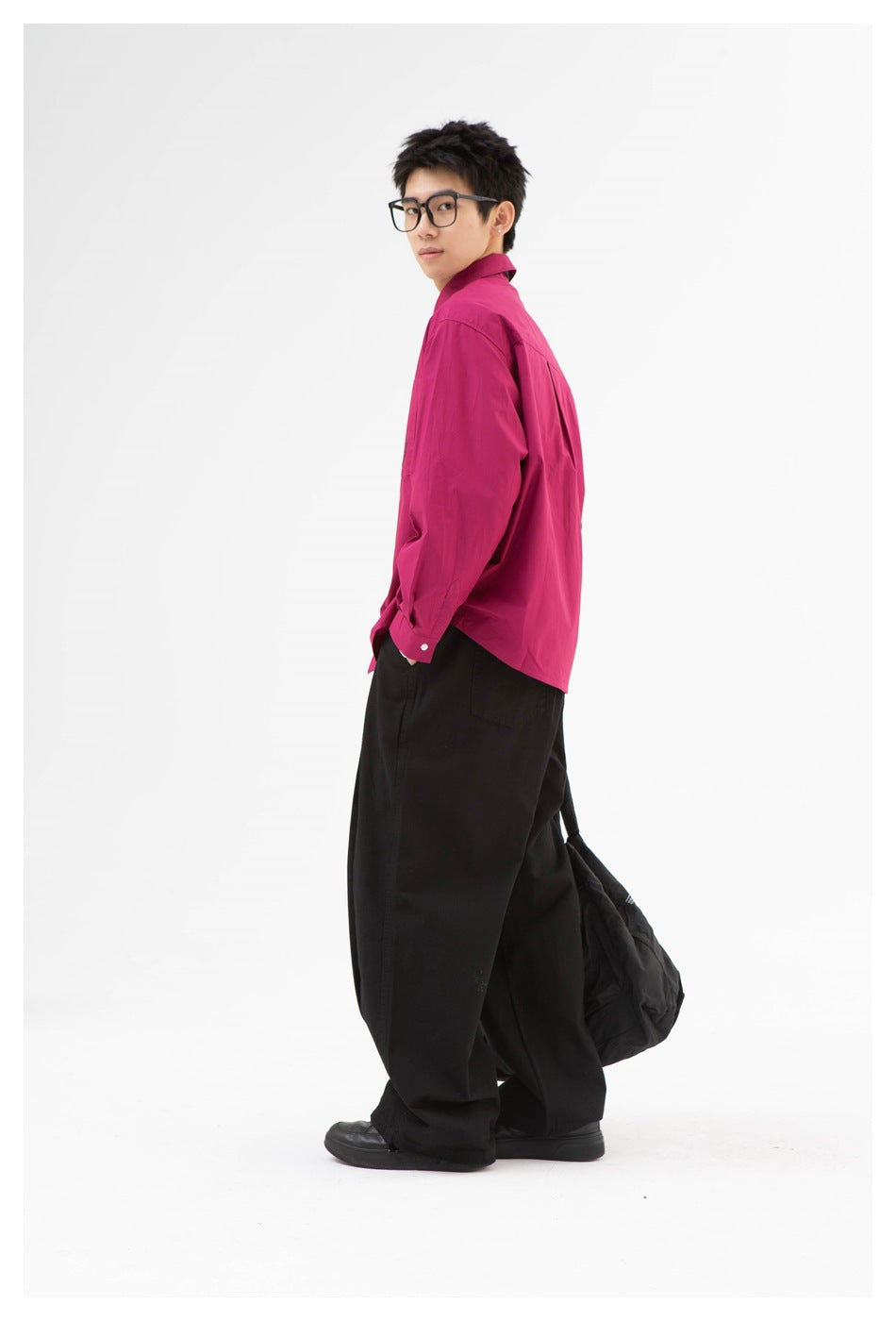 Side and back view of a model wearing a magenta button-up shirt and wide black trousers.