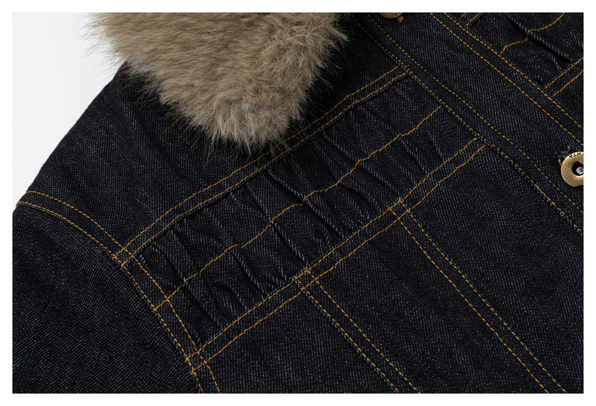 Close-up of dark denim panel seams and gathered stitching, with tan faux-fur trim and a gold-tone button partly visible.