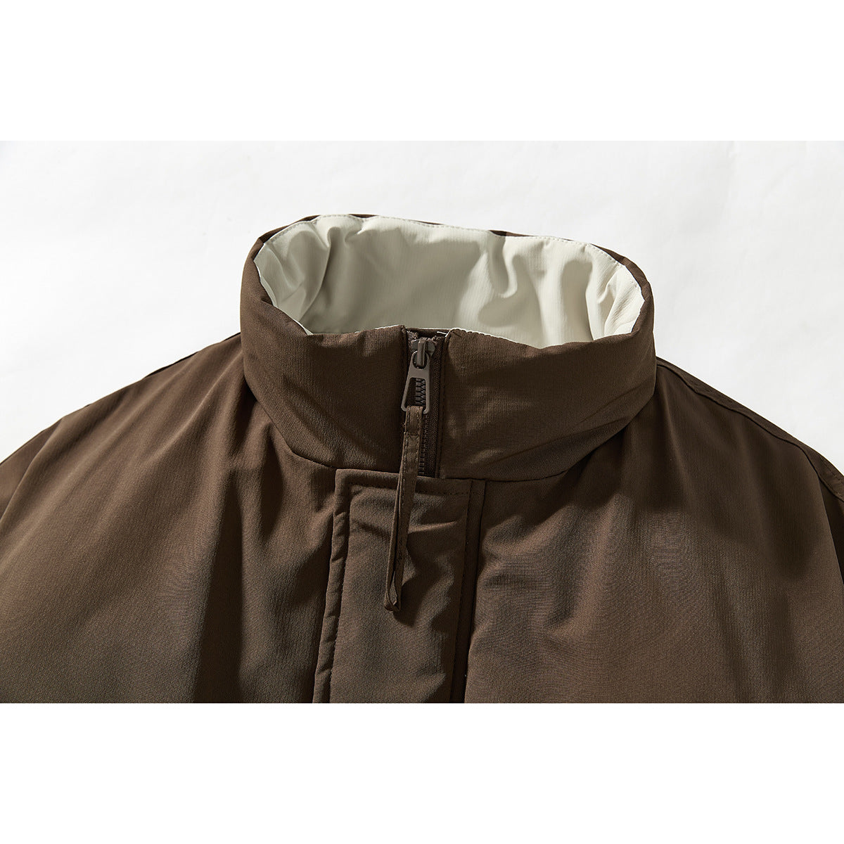 Close-up of a brown jacket's high collar, cream lining, and front zipper.