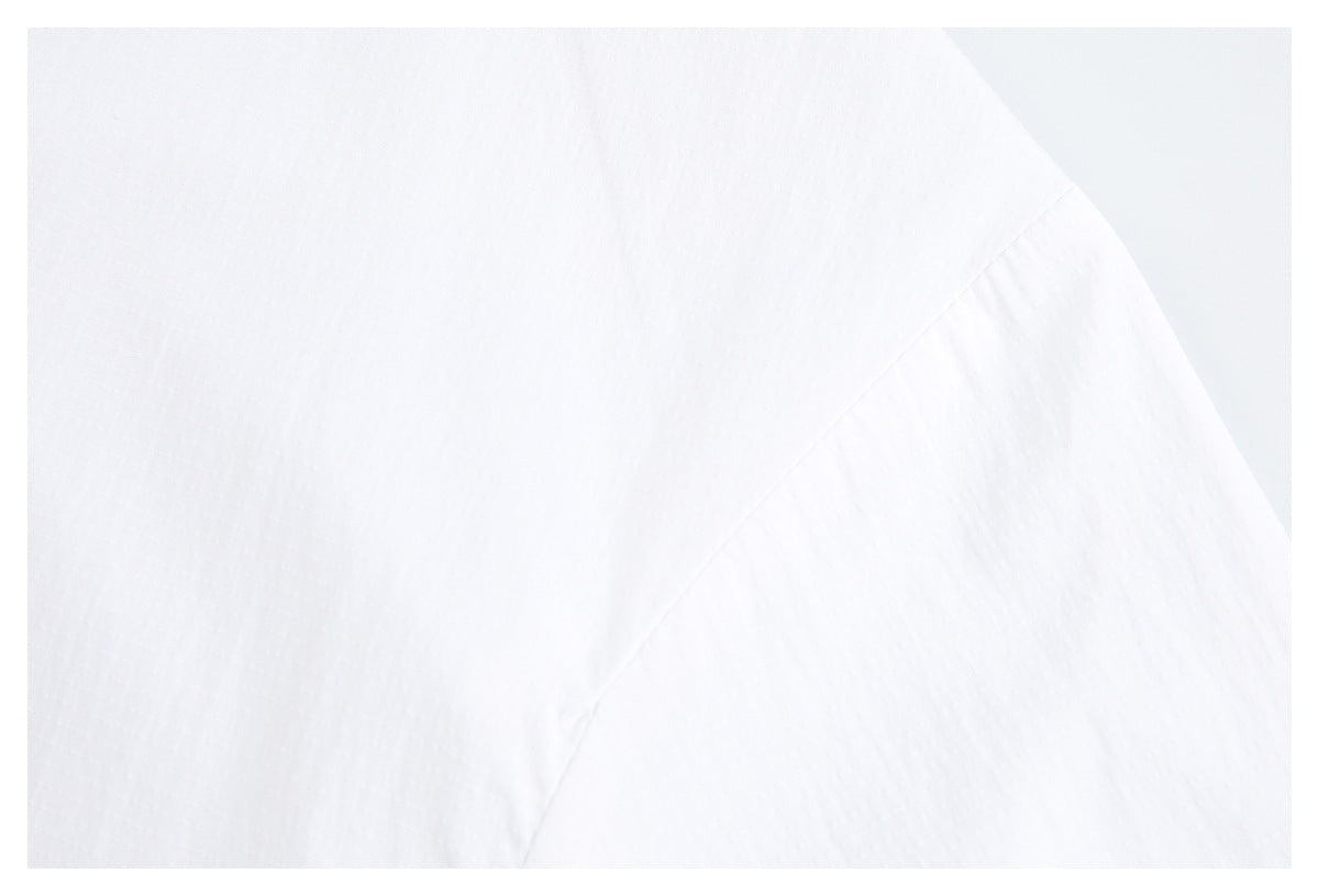 Close-up of white garment fabric and a curved stitched seam.