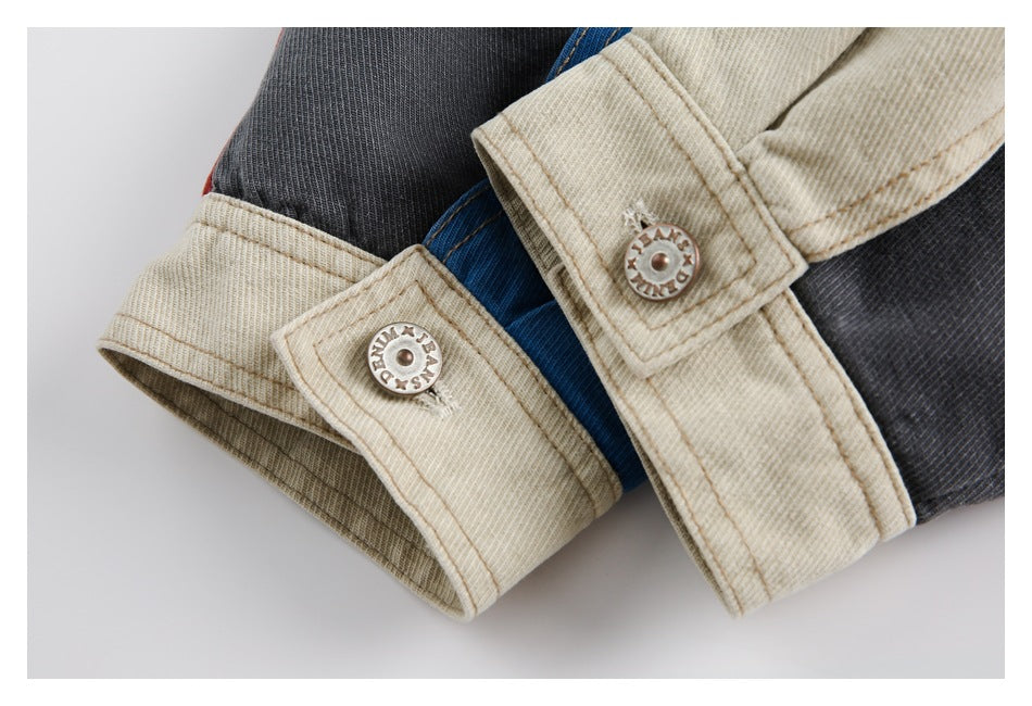 Close-up of cream cuffs with metal snaps against blue and charcoal panels.