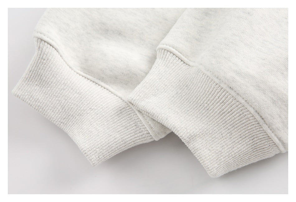 Close-up of two ribbed cuffs and seam detailing on a light heather-gray sweatshirt.