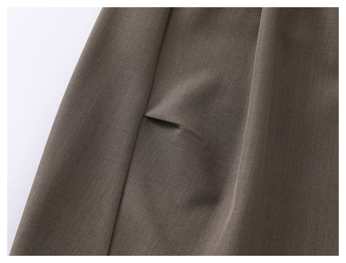 Close-up of taupe trouser fabric and a stitched seam with a small pleat.