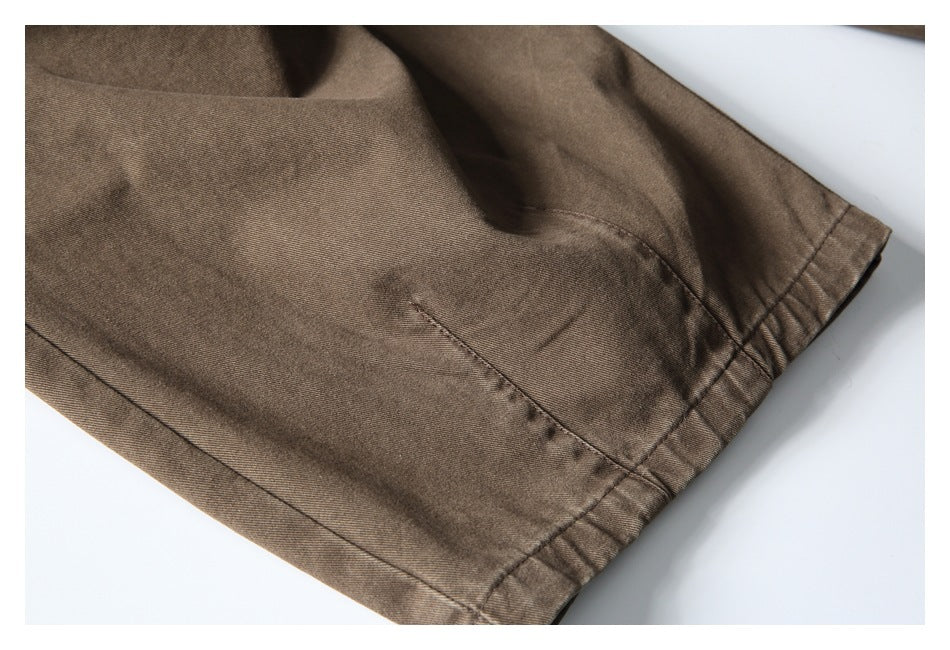 Close-up of the brown trouser leg hem and stitching on a light background.