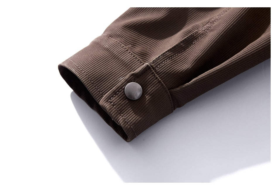 Close-up of a brown ribbed jacket sleeve cuff with a single gray snap button.