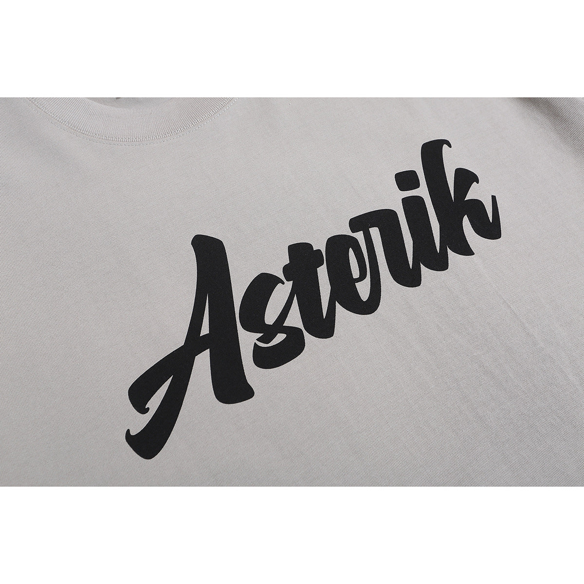 Close-up of a light gray T-shirt with bold black script lettering across the chest.