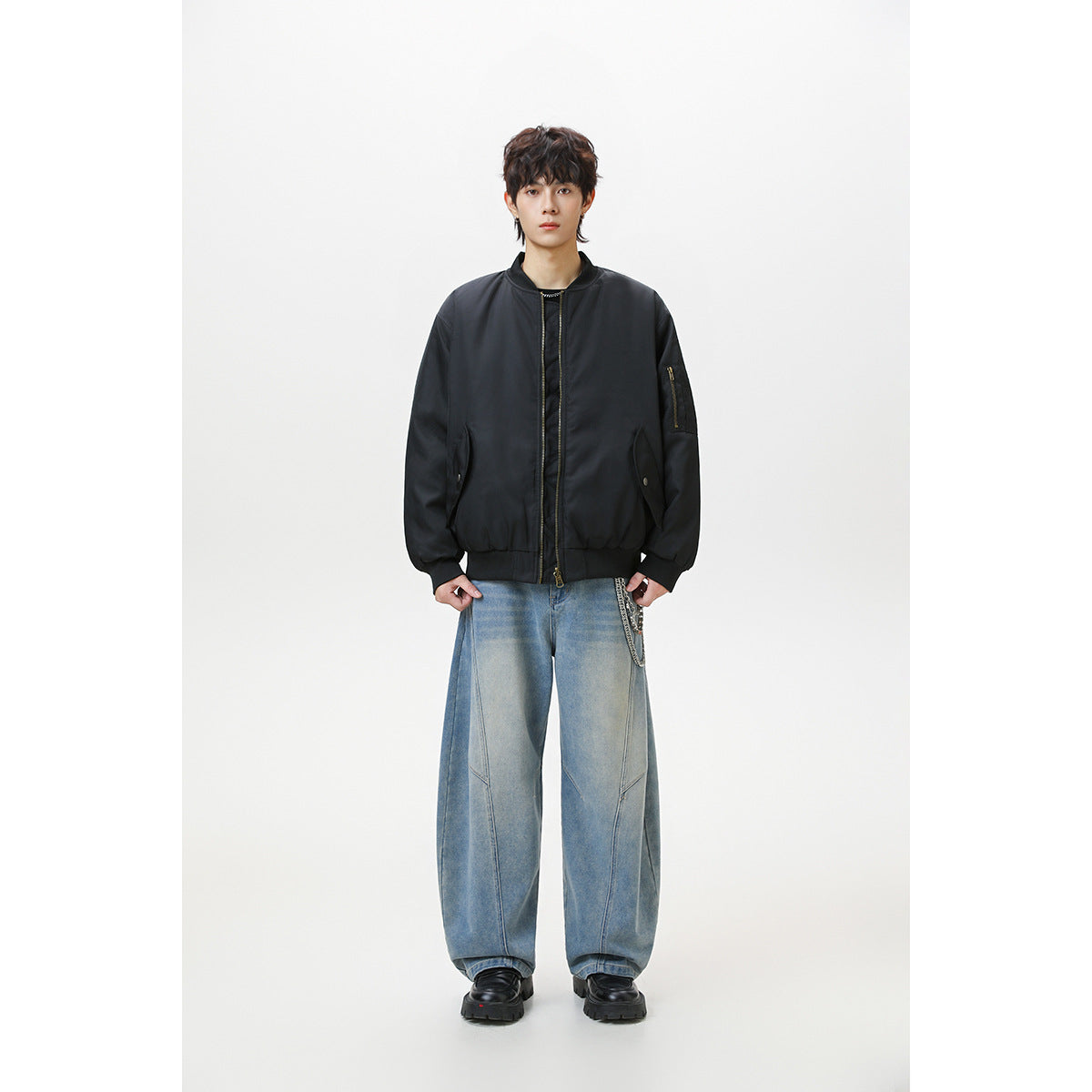 Full-length front view of a model wearing a black zip-front bomber jacket with a sleeve pocket.