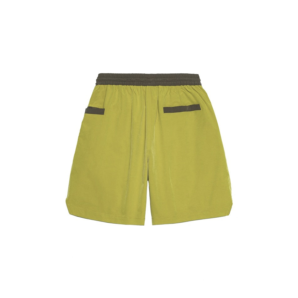 Back view of ginger-yellow shorts with olive-brown waistband and pocket trim on white background