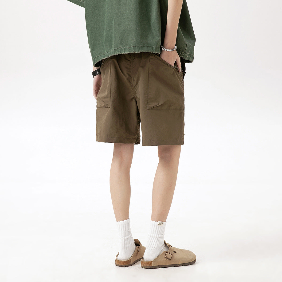 Back view of a model wearing brown knee-length shorts with rear patch pockets.