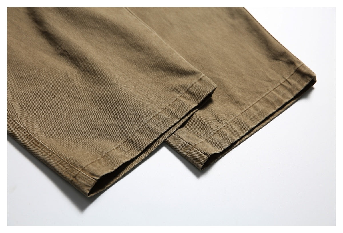 Close-up of the finished hems on the legs of tan-brown trousers.