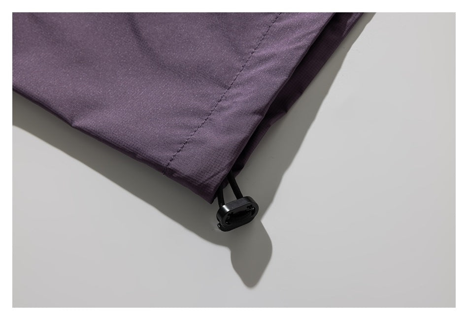 Close-up of a dark plum garment hem with an adjustable black drawcord toggle.