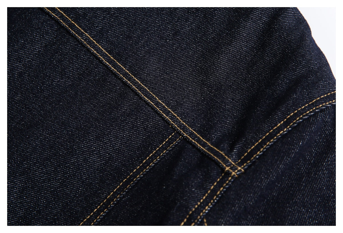 Close-up of dark indigo denim with prominent golden-brown double stitching and intersecting seams.