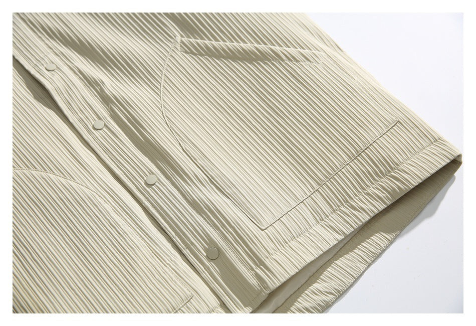 Close-up of the ivory jacket’s pleated front pocket, snap buttons, and hem.