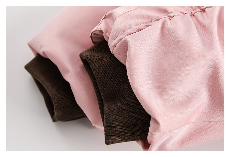 Close-up of pale pink jacket sleeves with dark brown ribbed cuffs.