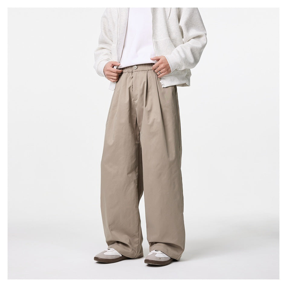 Front view of a model wearing taupe wide-leg trousers with a buttoned gathered waist and front pleats.