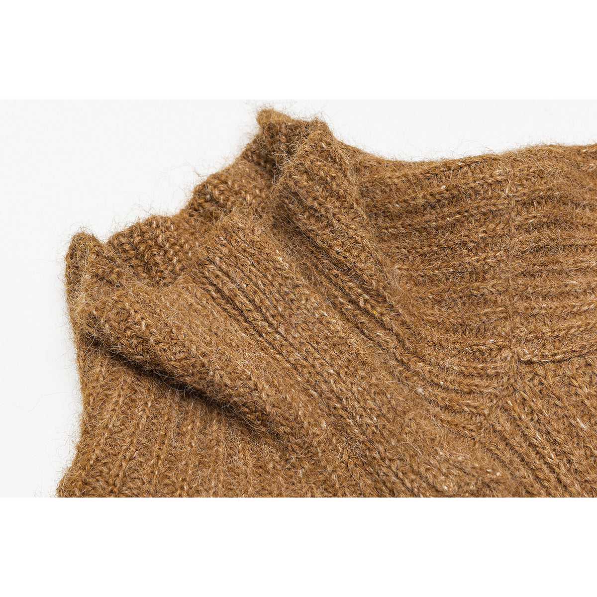 Close-up of a camel-brown knitted sweater showing a folded ribbed edge and textured stitches.