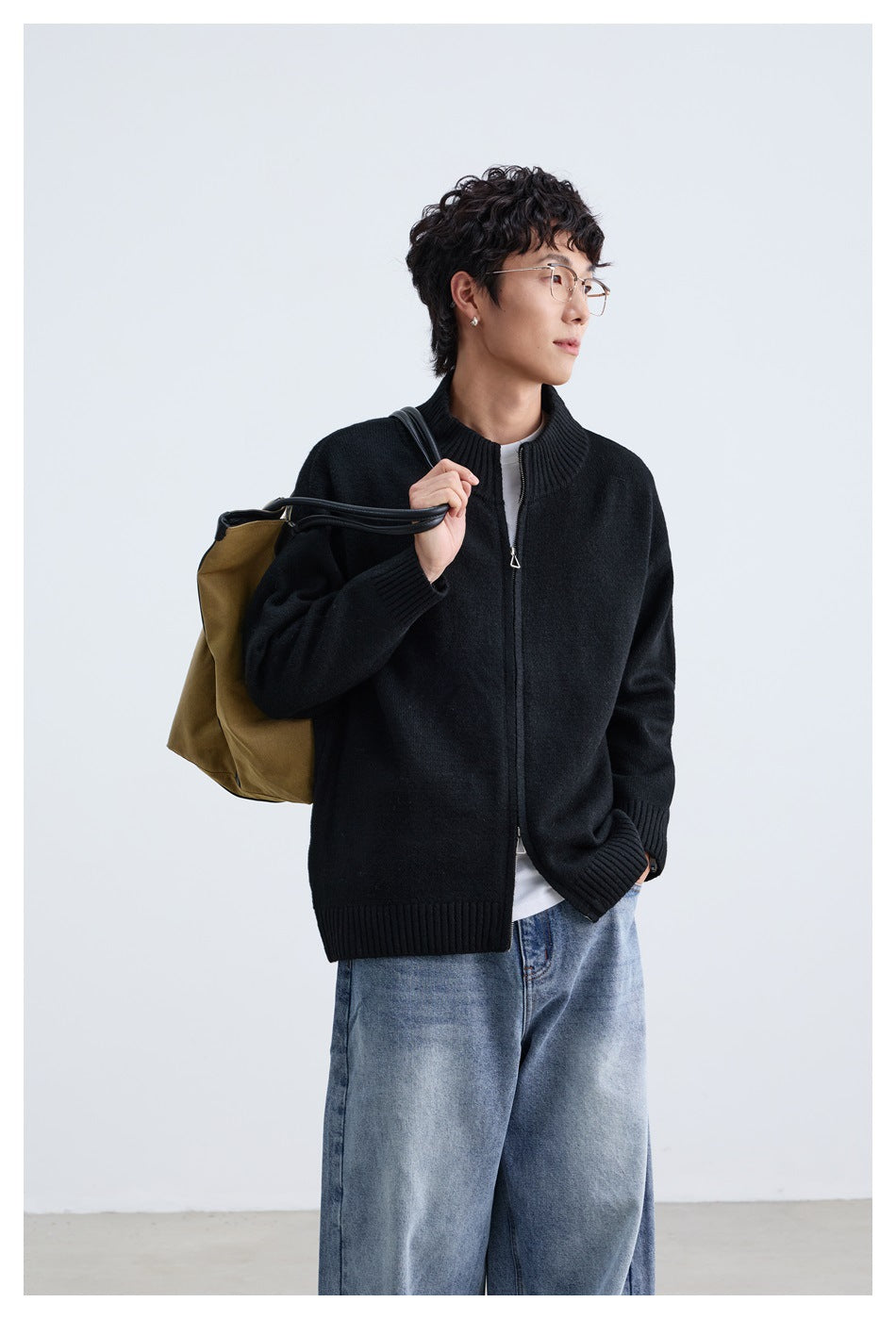 Model wearing a black zip-front cardigan with a ribbed stand collar, cuffs and hem, paired with light blue jeans.