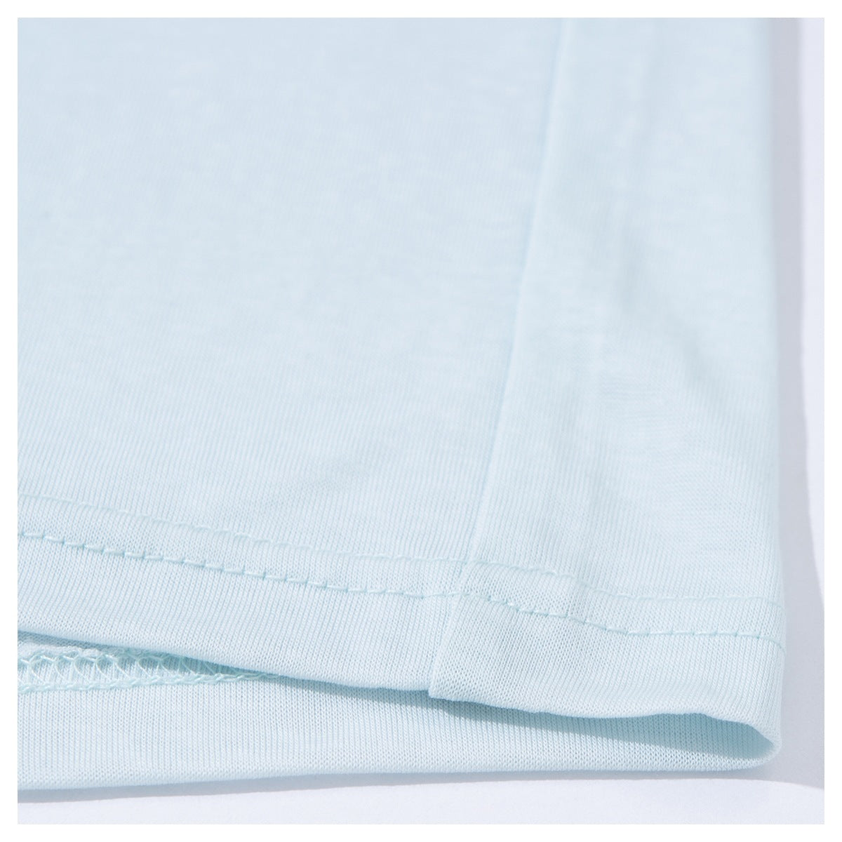 Close-up of the stitched bottom hem of a pale blue T-shirt.