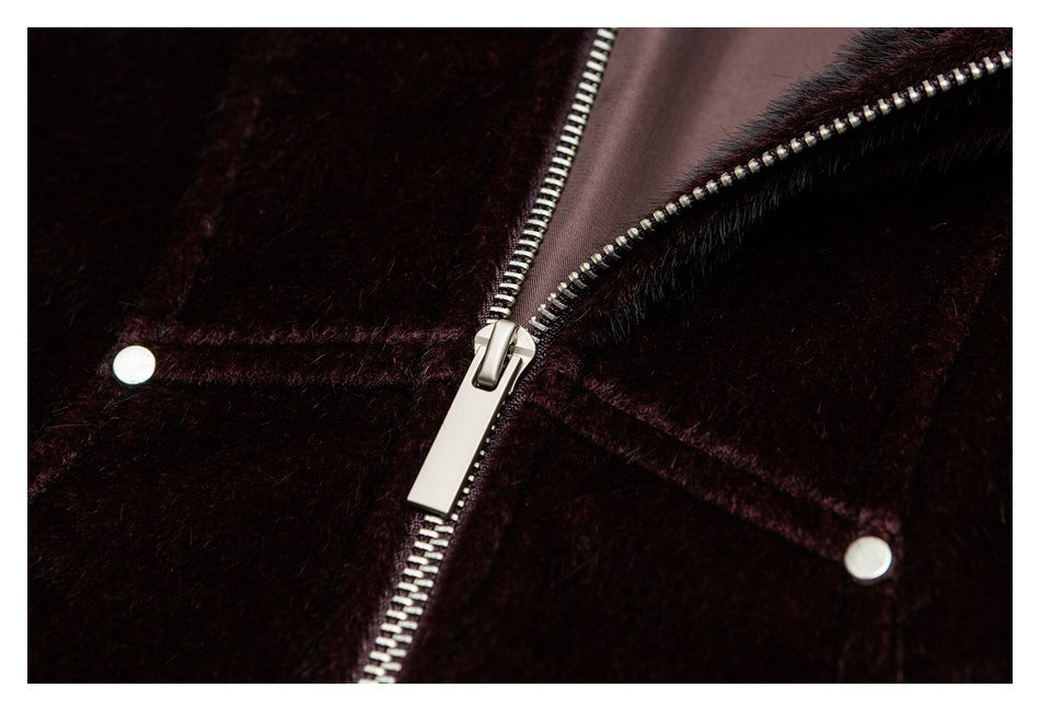 Close-up of a dark burgundy plush garment with a silver zipper and two round snaps.