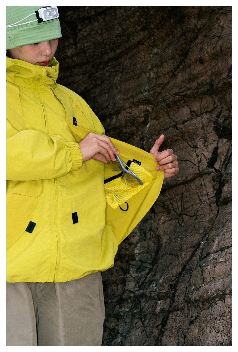 Close view of a yellow jacket opened to show an interior mesh pocket and a small hanging loop.