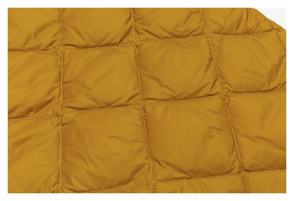 Close-up of mustard-gold padded jacket fabric with a grid of stitched quilted panels.