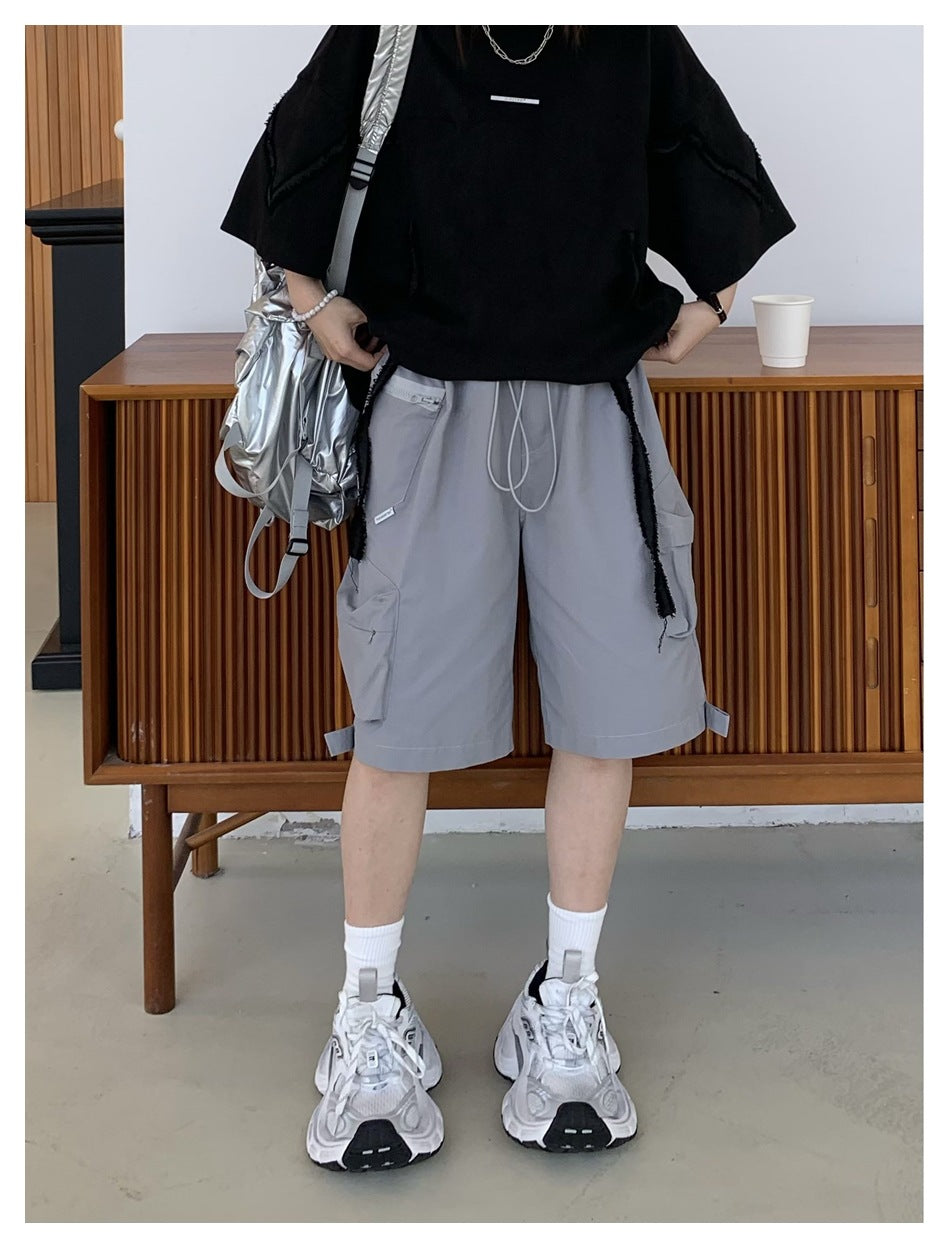Person wearing gray knee-length cargo shorts with a drawstring waist and multiple pockets, paired with a black top.